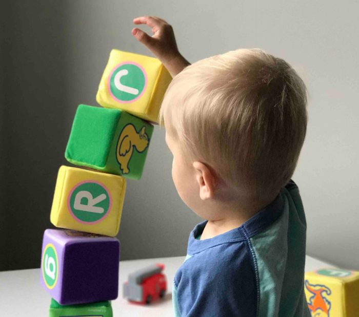 A one-year-old boy tries to stack blocks